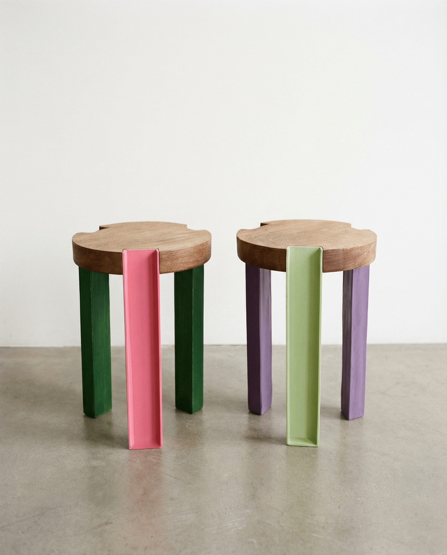 Two wooden stools with colorful legs on a plain background