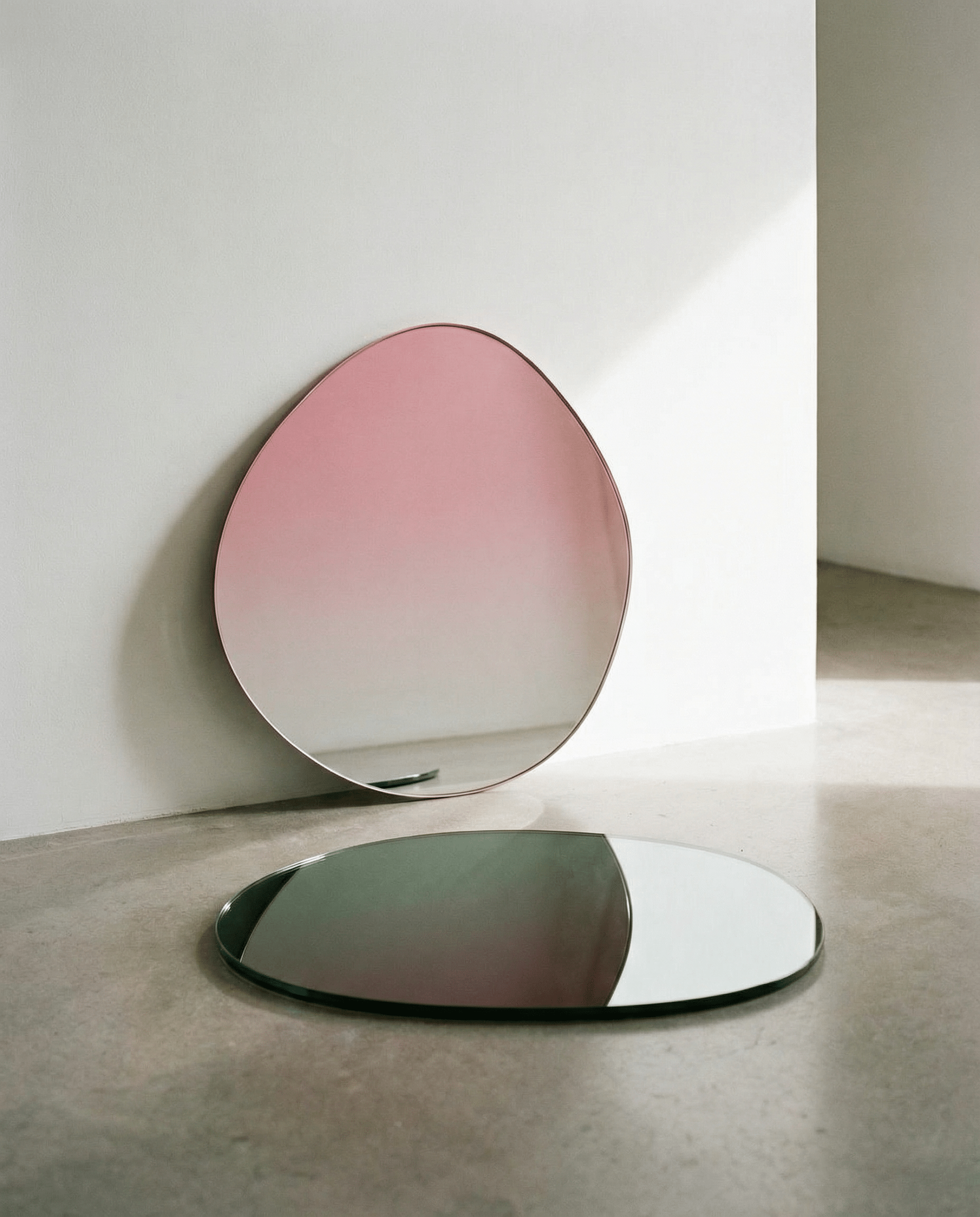 Two oval mirrors with gradient pink to clear design on a neutral background