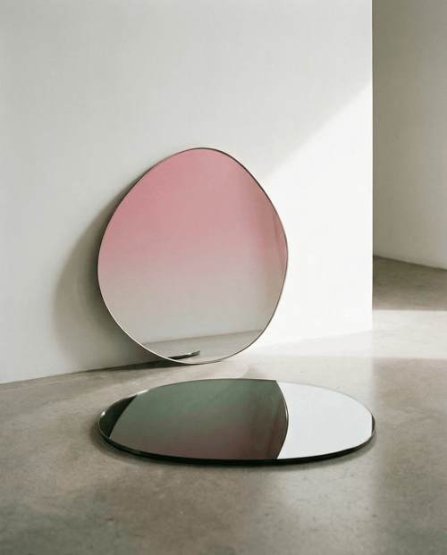 Two oval mirrors with gradient pink to clear design on a neutral background